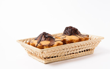 Fresh, homemade and flavored cupcakes in a wicker basket on a white background