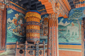Wall paintings and large prayer wheel inside the portico of the Trongsa Dzong, Bumthang, Bhutan.