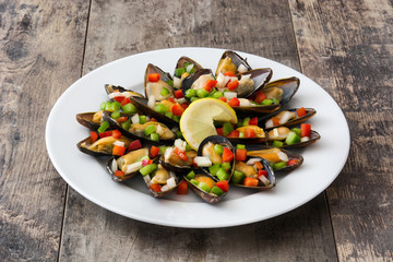 Steamed mussels with peppers and onion on wooden table