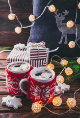 Hot chocolate with marshmallows and biscuits on Christmas decorations background.