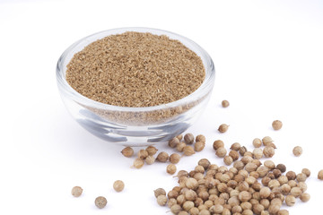 Ground coriander in glass bowl and seeds isolated on white background