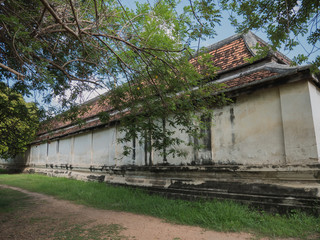 Dirt road through forest and yard in ancient Ayutthaya temple on sunny day