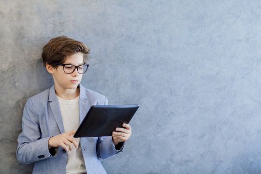 Teen schooler boy in eyeglasses holds tablet PC