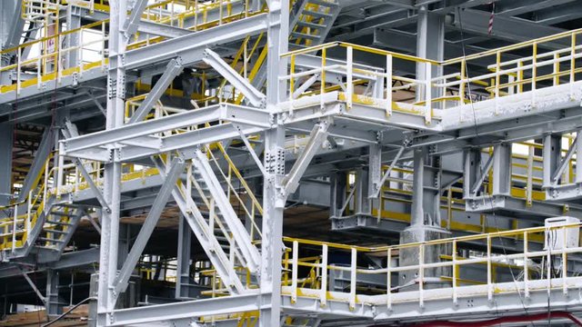 Scaffolding installation at a tank with process structures of refinery petrochemical plants in the background. Large steel structures for plant