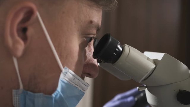 Dentist using dental microscope in modern dental office for operation of a woman patient -Dentistry. Male dentist with dental tools in clinic