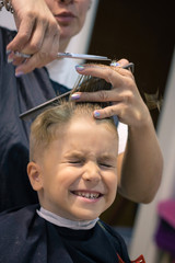 Small kid getting a haircut at hair salon.
