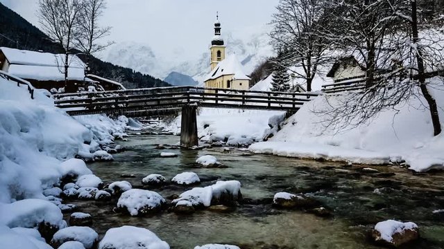 View of white water winter river landscape in Ramsau, Bavarian Alps with famous Parish Church of St. Sebastian in the village of Ramsau, Nationalpark Berchtesgadener Land, Upper Bavaria, German