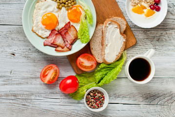 Breakfast with bacon and fried eggs, fruit and oatmeal. Morning coffee in a white cup. Menu for the cafe.