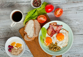 Breakfast with bacon and fried eggs, fruit and oatmeal. Morning coffee in a white cup. Menu for the cafe.