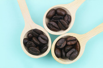Coffee beans on wooden spoons on blue background
