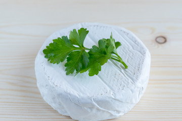 camembert with parsley on wooden background