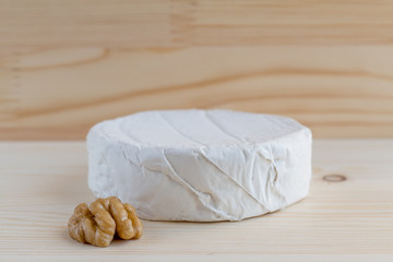Fototapeta na wymiar camembert cheese and walnut on wooden background