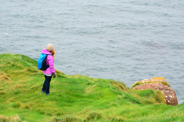 Backpacker in a pink jacket by the sea