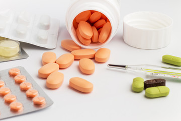 Pills and thermometer on a white background
