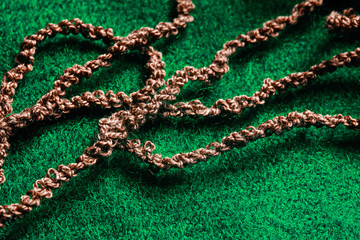 Fototapeta na wymiar Brown woolen threads on a green fabric background
