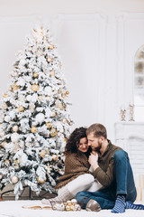 Beautiful young couple hugging near Christmas tree. Christmas and New Year concept