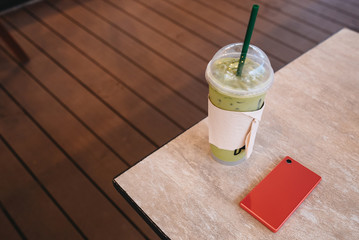 Coffee cup and smartphoneon table in coffee shop.