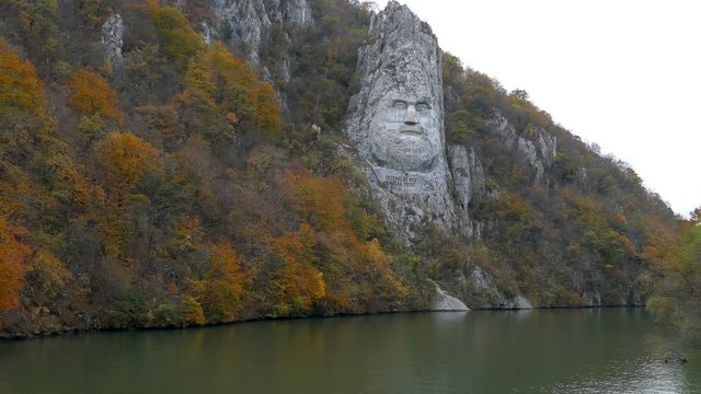 Autumn at the Danube Gorges, the border between Romania and Serbia. View with the Decebal King's Head sculpted in rock and inscription "DECEBAL REX - DRAGAN FECIT" (Decebal King - Made by Dragan).