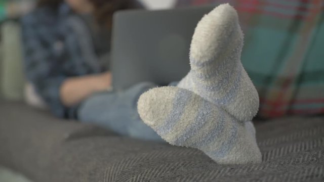 Woman Wearing Socks While Using Laptop On Sofa