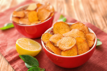 Bowl with yummy sweet potato chips on table