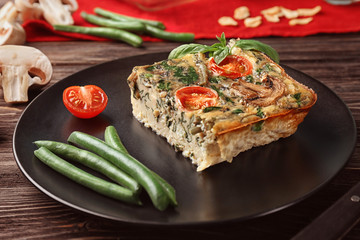 Black plate with delicious spinach frittata on table