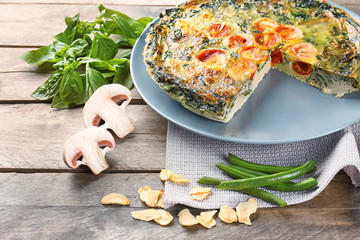 Plate with delicious spinach frittata on wooden background