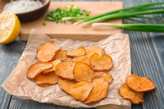 Yummy sweet potato chips on wooden table