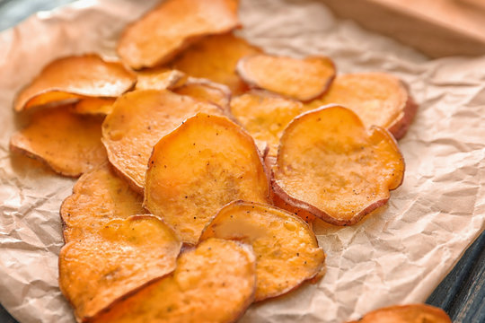 Yummy sweet potato chips on table