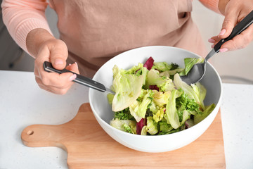 Mature woman making salad in kitchen
