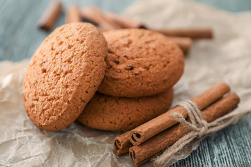 Tasty oatmeal cookies and cinnamon sticks on table, closeup