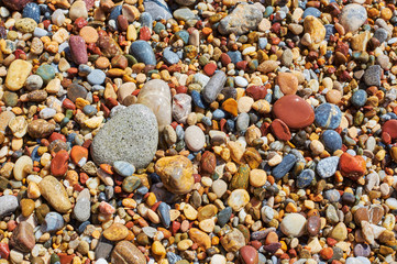 Multicolored sea pebbles in the wave on the shore
