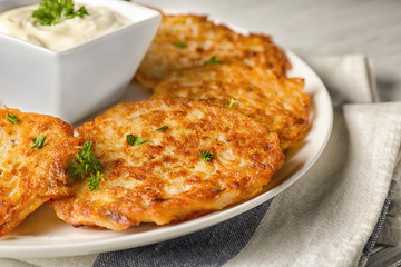 Plate with Hanukkah potato pancakes and sauce on table, closeup
