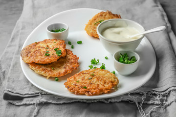 Plate with Hanukkah potato pancakes and sauce on table