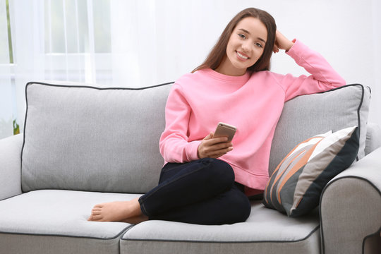 Young woman with mobile phone on sofa at home