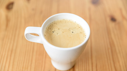 Kaffee Crema ain einer weißen Tasse auf einem Holztisch