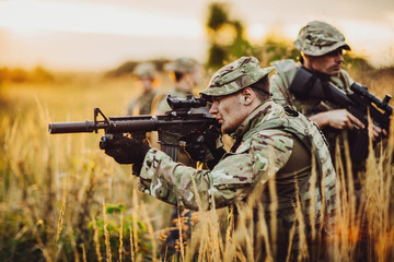 Fototapeta premium Rangers shooting with his weapon, rifle at sunset. War, army, military concept.