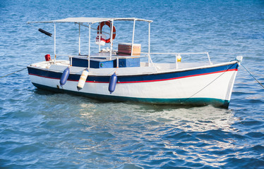 White wooden fishing boat anchored in port