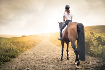 Foto op Canvas Meisje rijdt op haar paard op een pad in de heuvels © merla