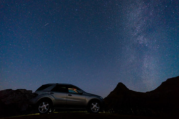 Fototapeta na wymiar Night landscape with a car on the background of the milky way