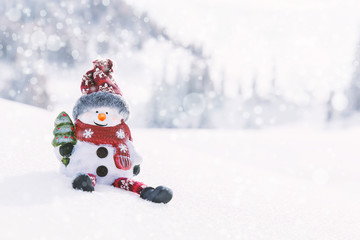 Schneemann mit Christbaum sitzt im Schnee