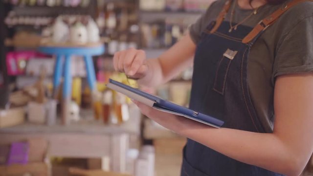 Midsection Of Female Deli Owner Using Tablet Computer In Delicatessen