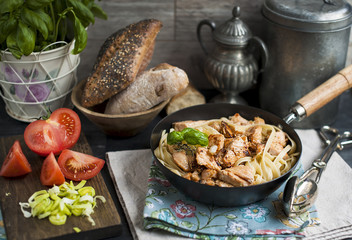 black frying pan with pasta, vegetables and bread for lunch