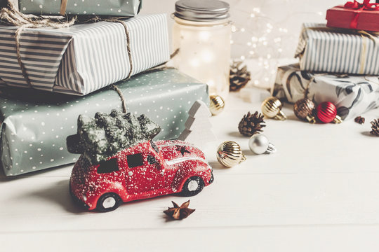 Modern Christmas Ornaments And Car Toy With Tree, Presents Cones Anise On White Wooden Background. Merry Christmas Concept. Seasonal Greetings. Happy Holidays, Xmas Card, Hygge