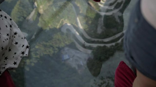 POV view of the legs in red boot covers walking along sgass sky walk at Tianmenshan National Park in China