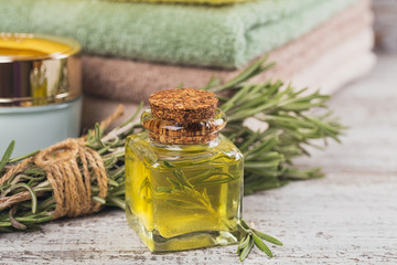 Natural cosmetic oil and natural handmade soap with rosemary on rustic wooden background.