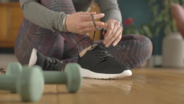 Rack Focus Of Fit Woman Tying Shoe Lace By Dumbbells