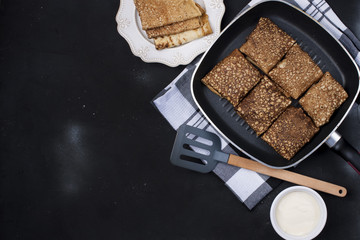 pancakes in a frying pan and sauce on a black background