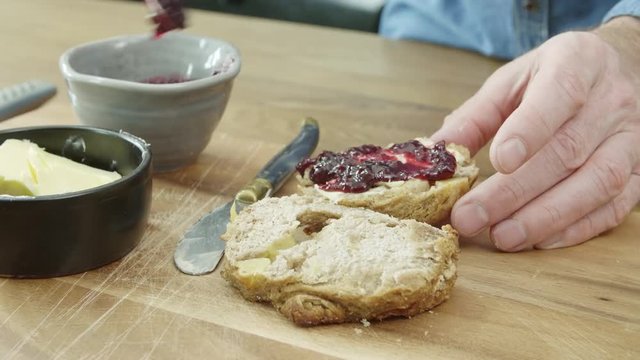 Close-up Of Man's Hands Spreading Jam On Bread With Spoon