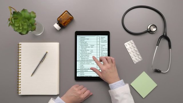 Overhead Top View Of Doctor Examining Medical Report On Digital Tablet