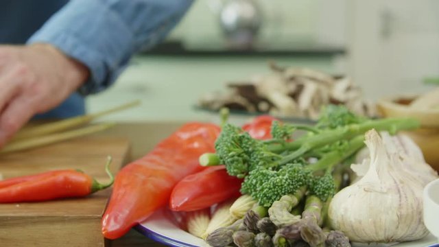 Vegetables In Plate By Man Cutting Spring Onion At Kitchen
